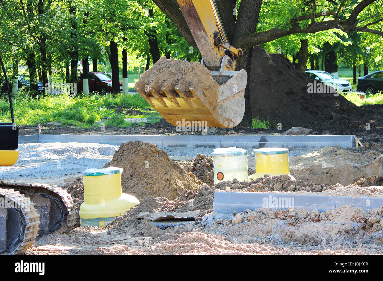 Excavator digs to plastic tank gas oil catcher in the ground during the construction of a car park for tourist buses, Russia Stock Photo