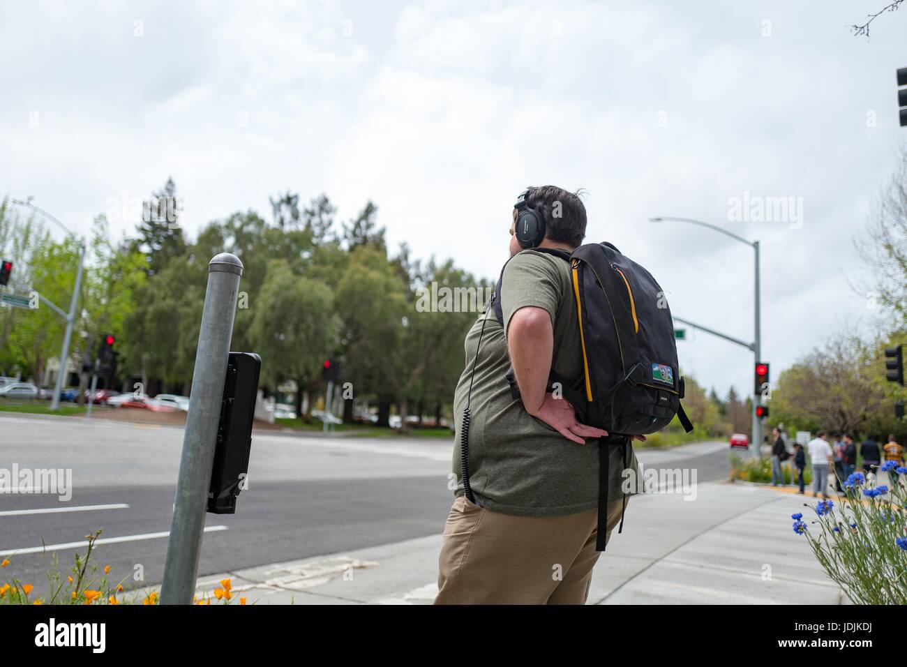 A young male technology worker, wearing headphones and a backpack, stands at an intersection at the Googleplex, the Silicon Valley headquarters of search engine and technology company Google Inc, Mountain View, California, April 7, 2017. Stock Photo