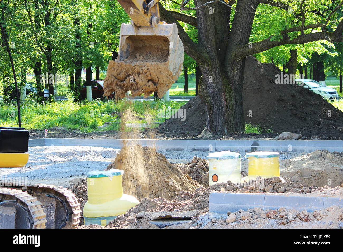 Excavator digs to plastic tank gas oil catcher in the ground during the construction of a car park for tourist buses, Russia Stock Photo