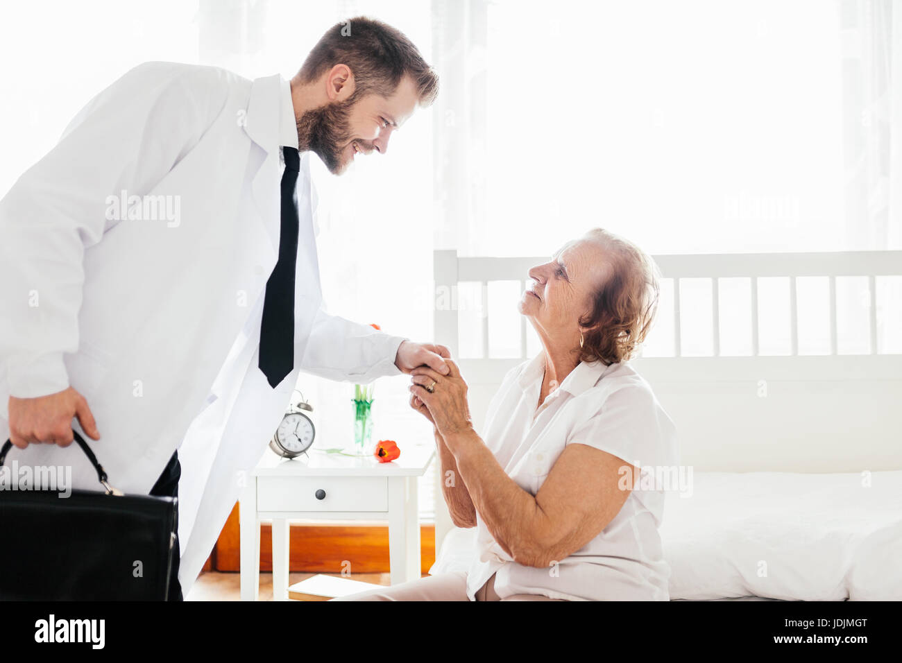 Providing care and support for elderly. Doctor visiting elderly patient at home. Stock Photo