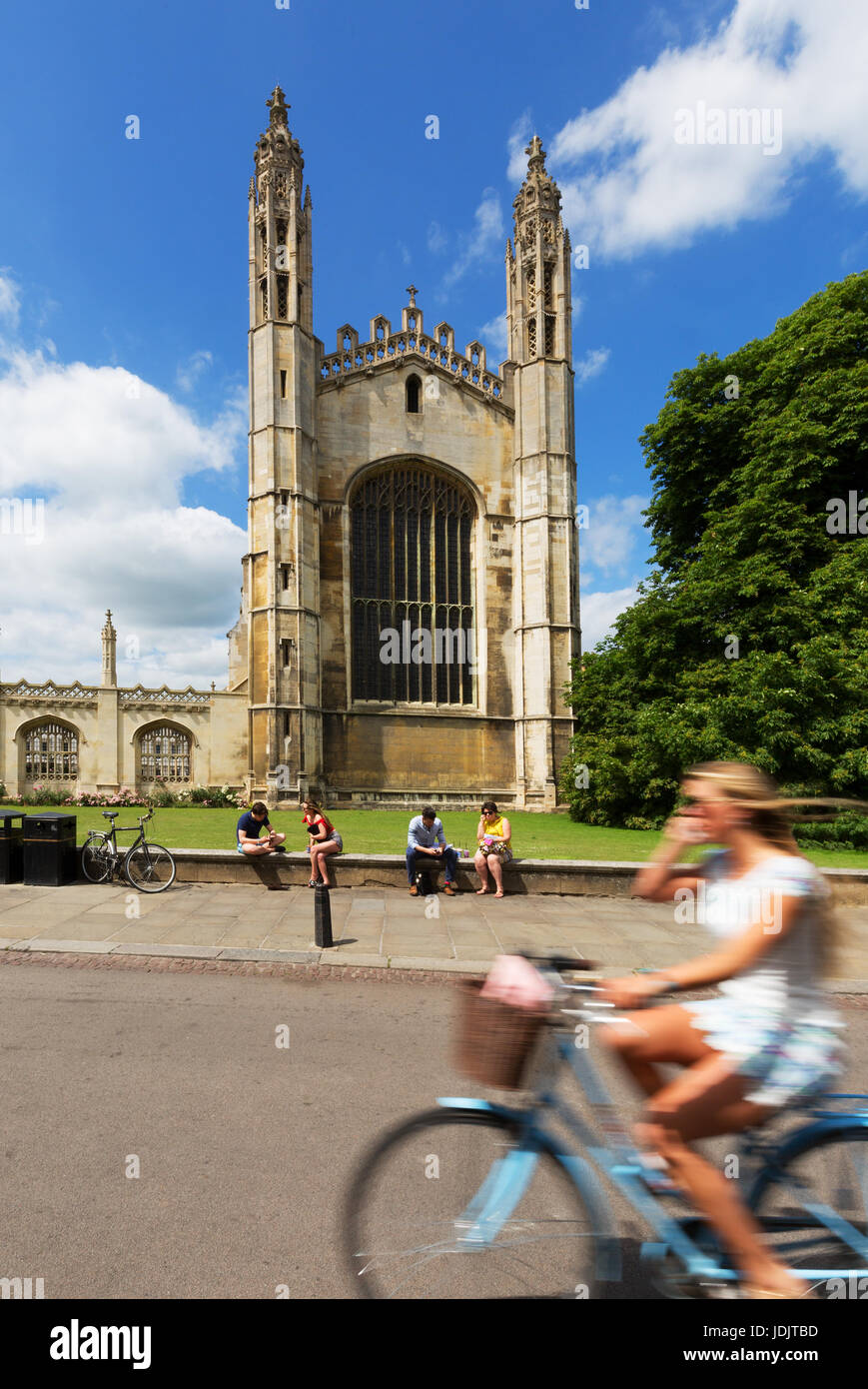 A woman cycling past Kings College Chapel, Cambridge city centre in summer; Cambridge England UK Stock Photo