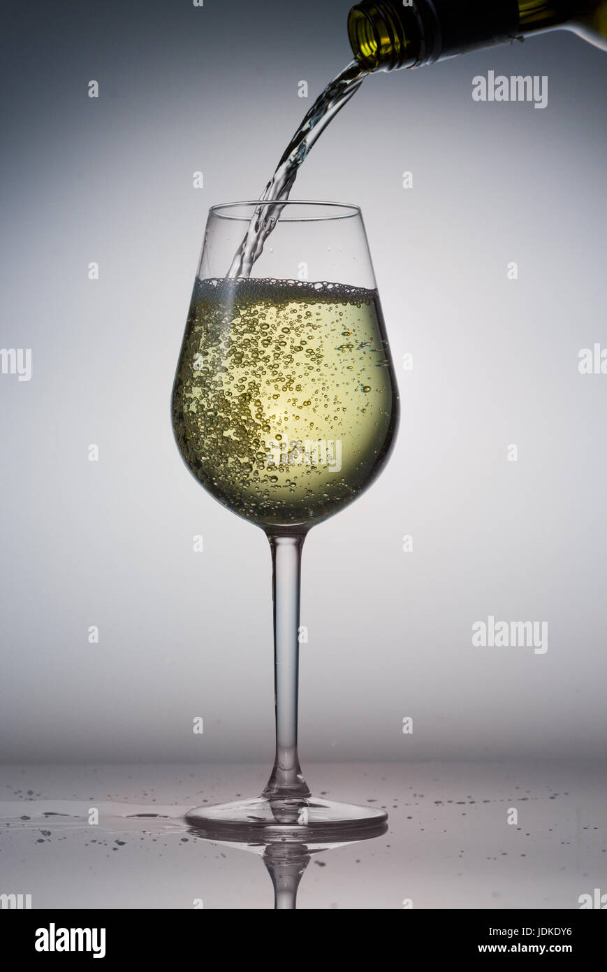 Pouring white wine from bottle to glass Stock Photo - Alamy