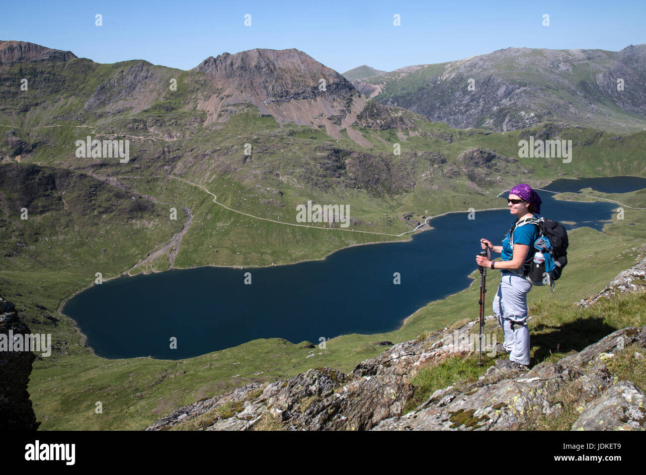 Female hiker looking across Llyn Llydaw, over to the knife edge arete ridge of Crib Goch, in the Snowdonia National Park in North wales. Stock Photo