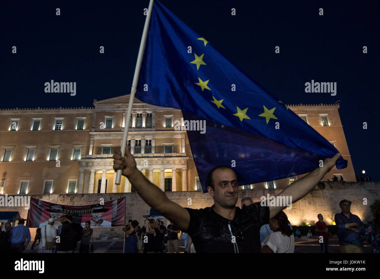 Protesters wave Greek flags and placards as they shout slogans. More ...