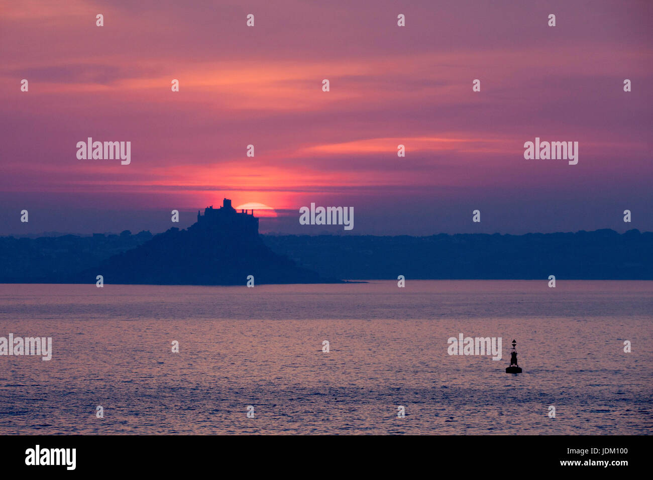 Penzance, Cornwall, UK. 21st June, 2017. A spectacular midsummer sunrise behind the castle on St Michael's Mount. Mount's Bay is a large, sweeping bay on the south west coast of Cornwall with many sandy beaches and dramatic cliff walks in either direction from Penzance. cliffs i Credit: Mike Newman/Alamy Live News Stock Photo