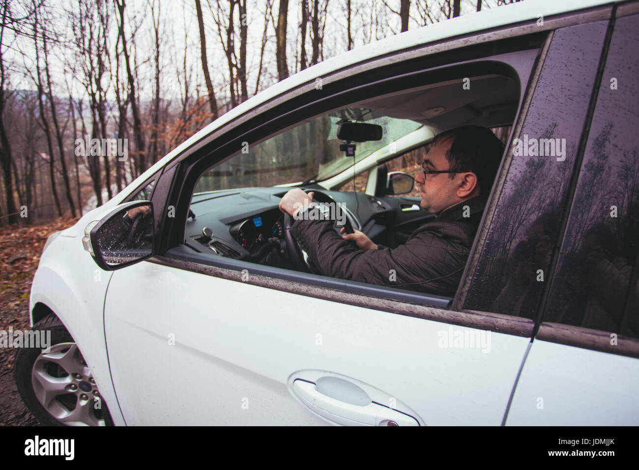 A young man driving a car traveling in the autumn rainy day Stock Photo ...