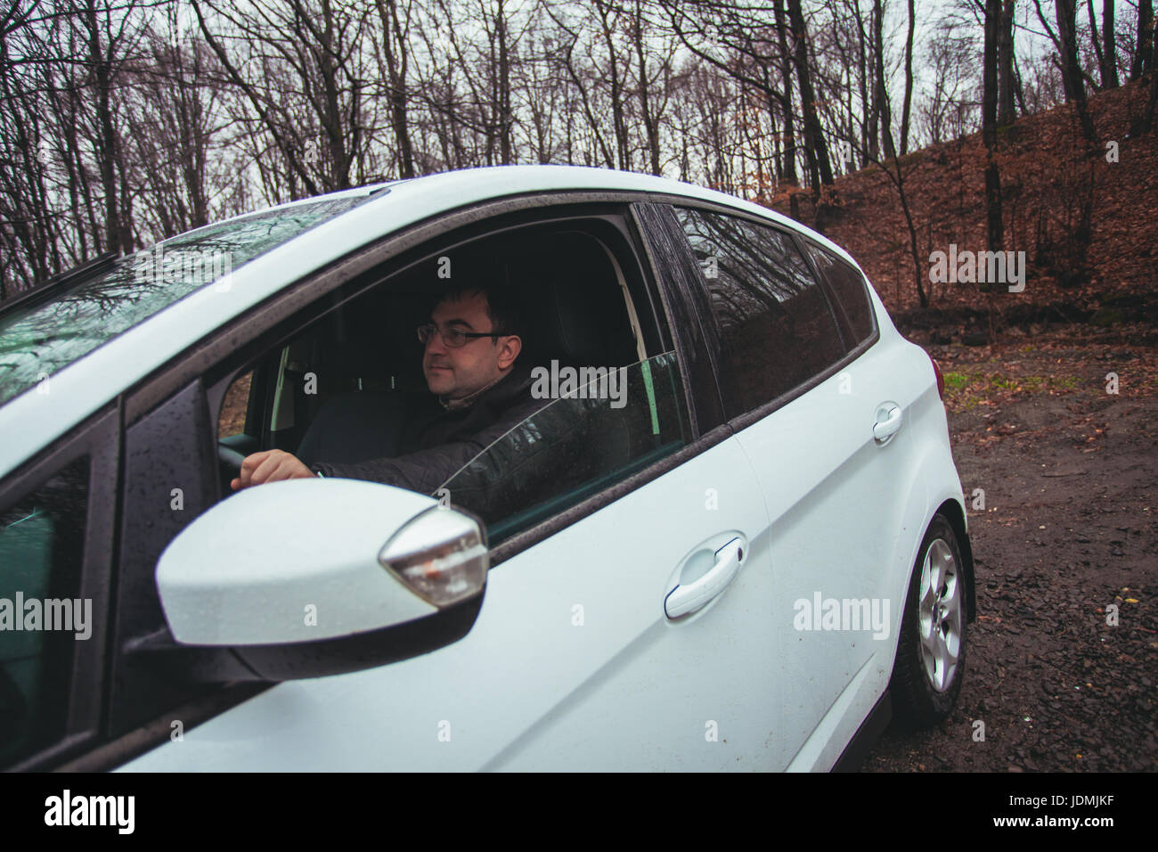 A young man driving a car traveling in the autumn rainy day Stock Photo ...