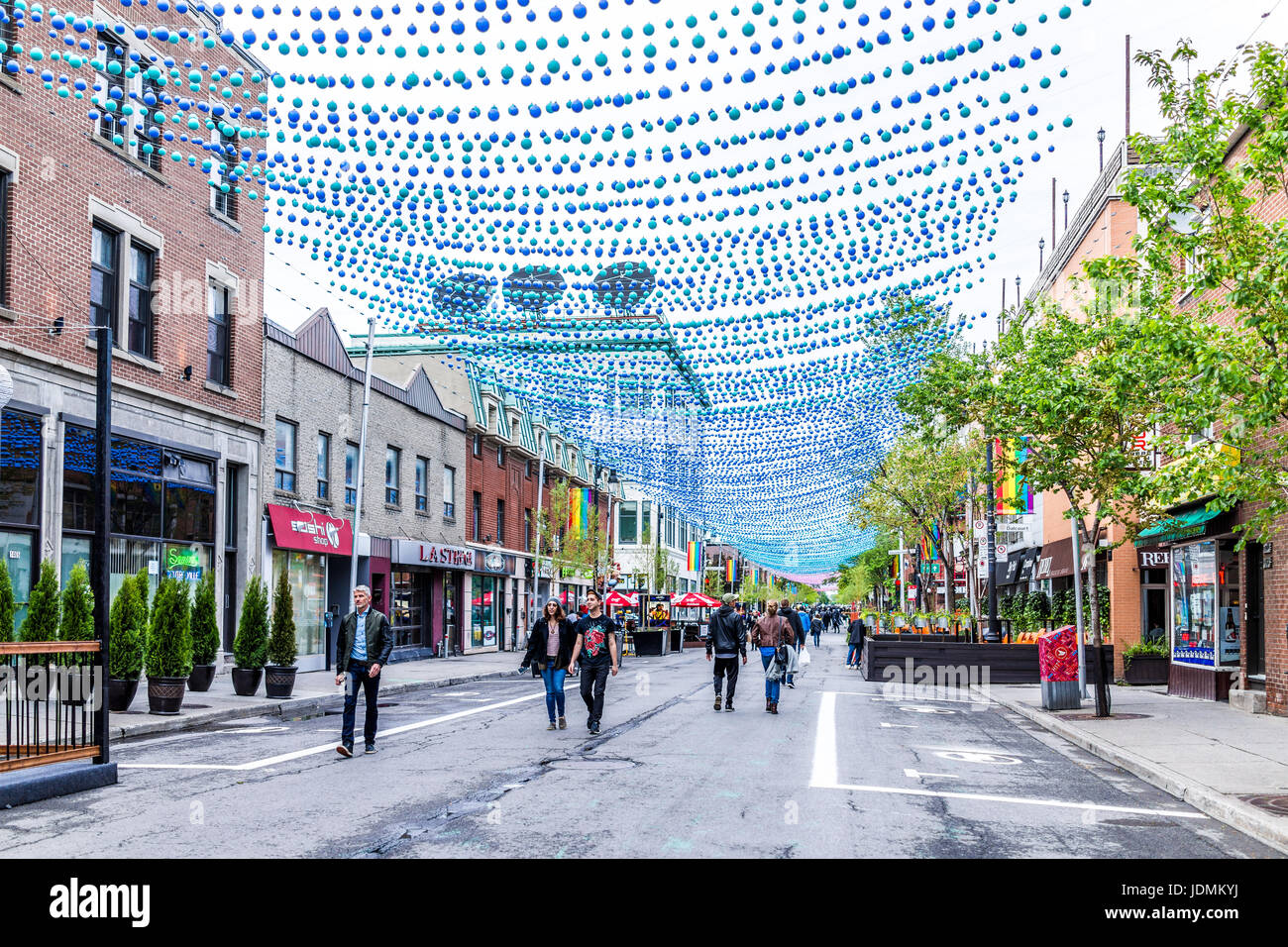Montreal, Canada - May 26, 2017: People walking on Sainte Catherine street in Montreal's Gay Village in Quebec region with hanging decorations Stock Photo