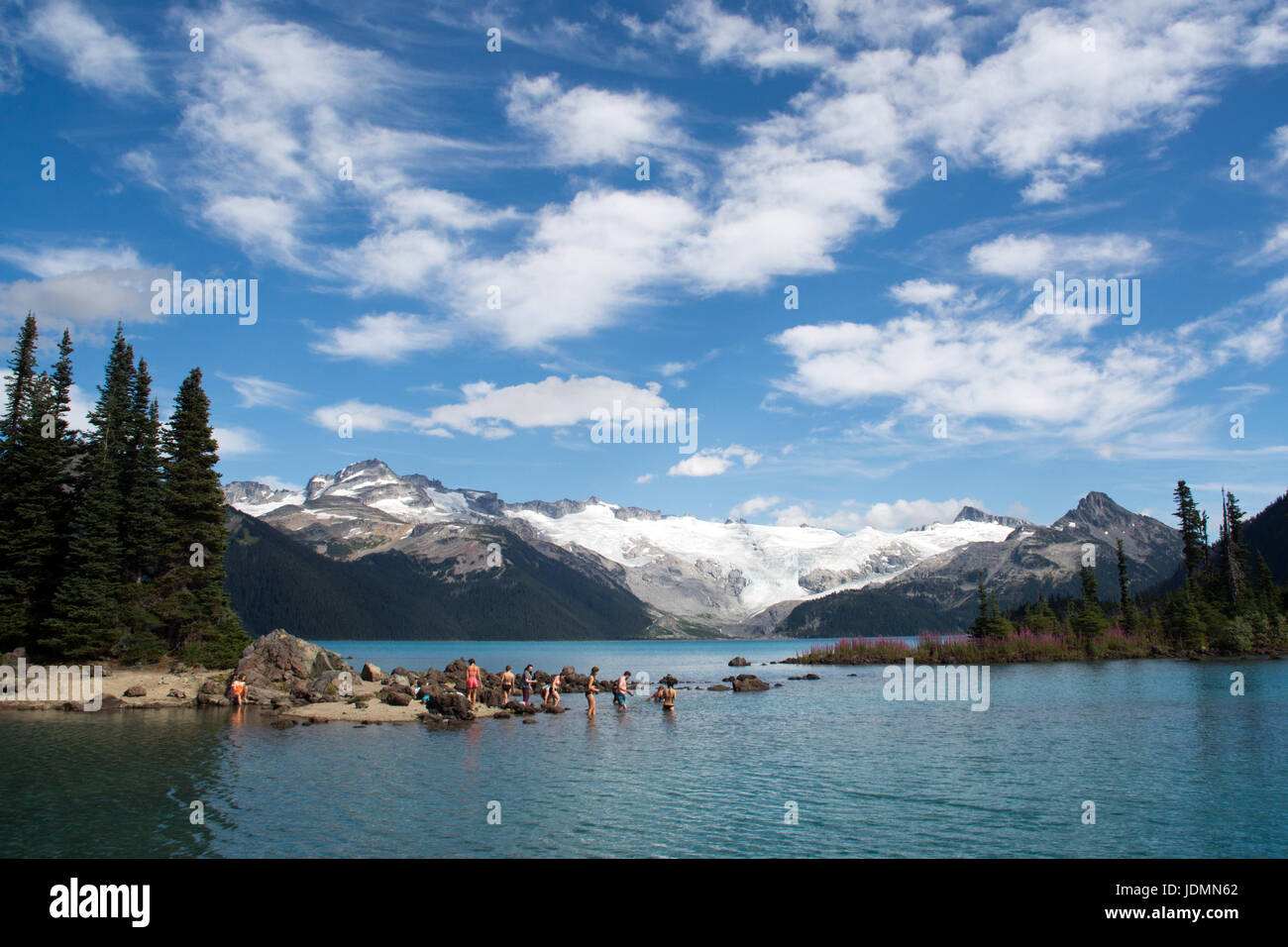 A group of people bathing in Garibaldi Lake, a glacial lake in the Coast Mountains of British Columbia, Canada, Stock Photo