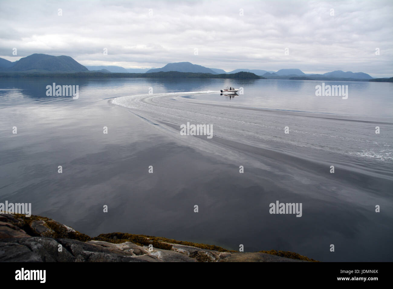 A motorboat cutting through the glassy waters of Spiller Channel in the Great Bear Rainforest, British Columbia, Canada. Stock Photo