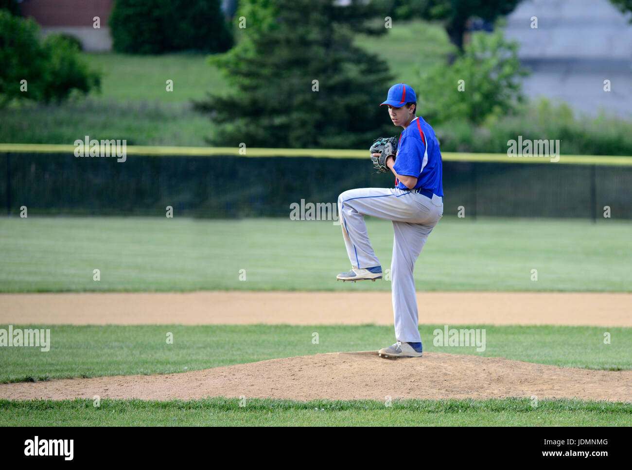 teenage boy winding up and ready to throw a baseball on the pitching mound Stock Photo