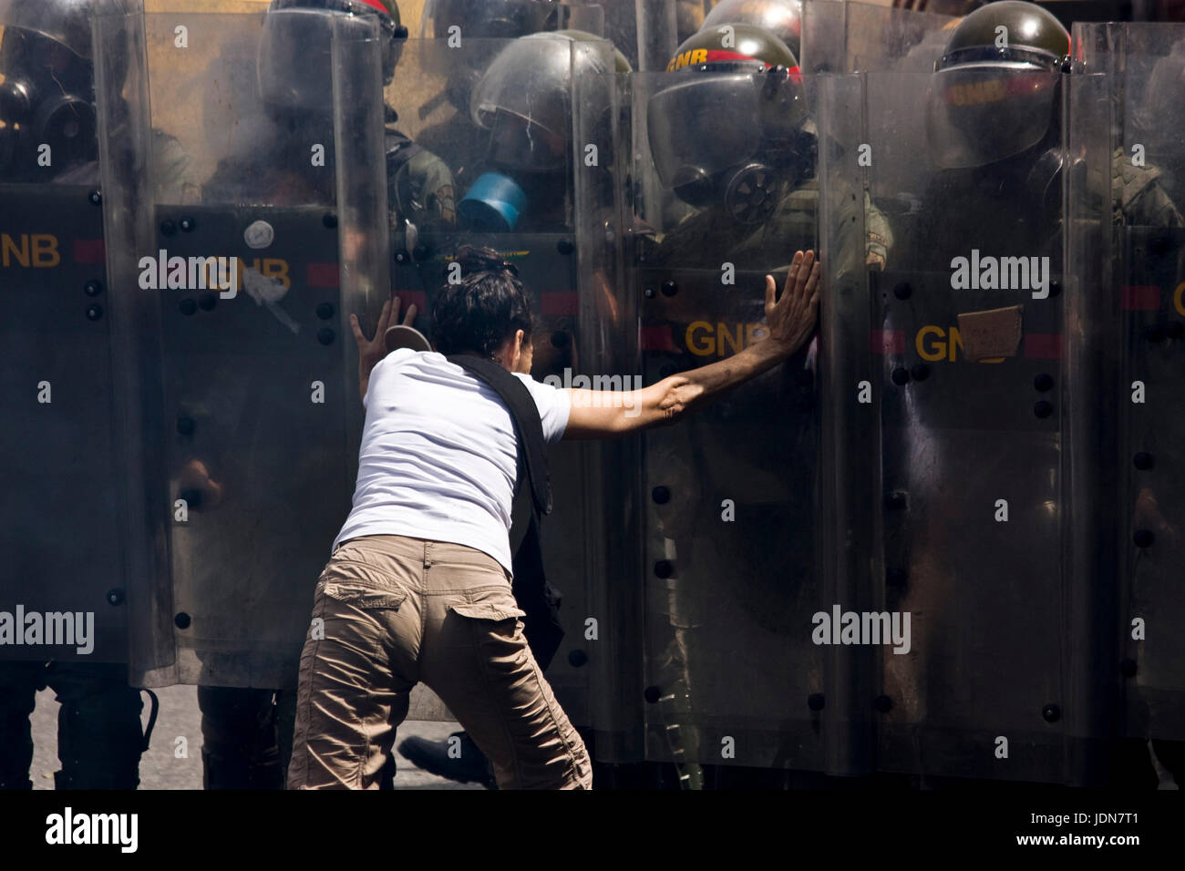 A woman tries to stop a group of members of the Bolivarian National Guards from dispersing protesters on a highway in Caracas. Stock Photo