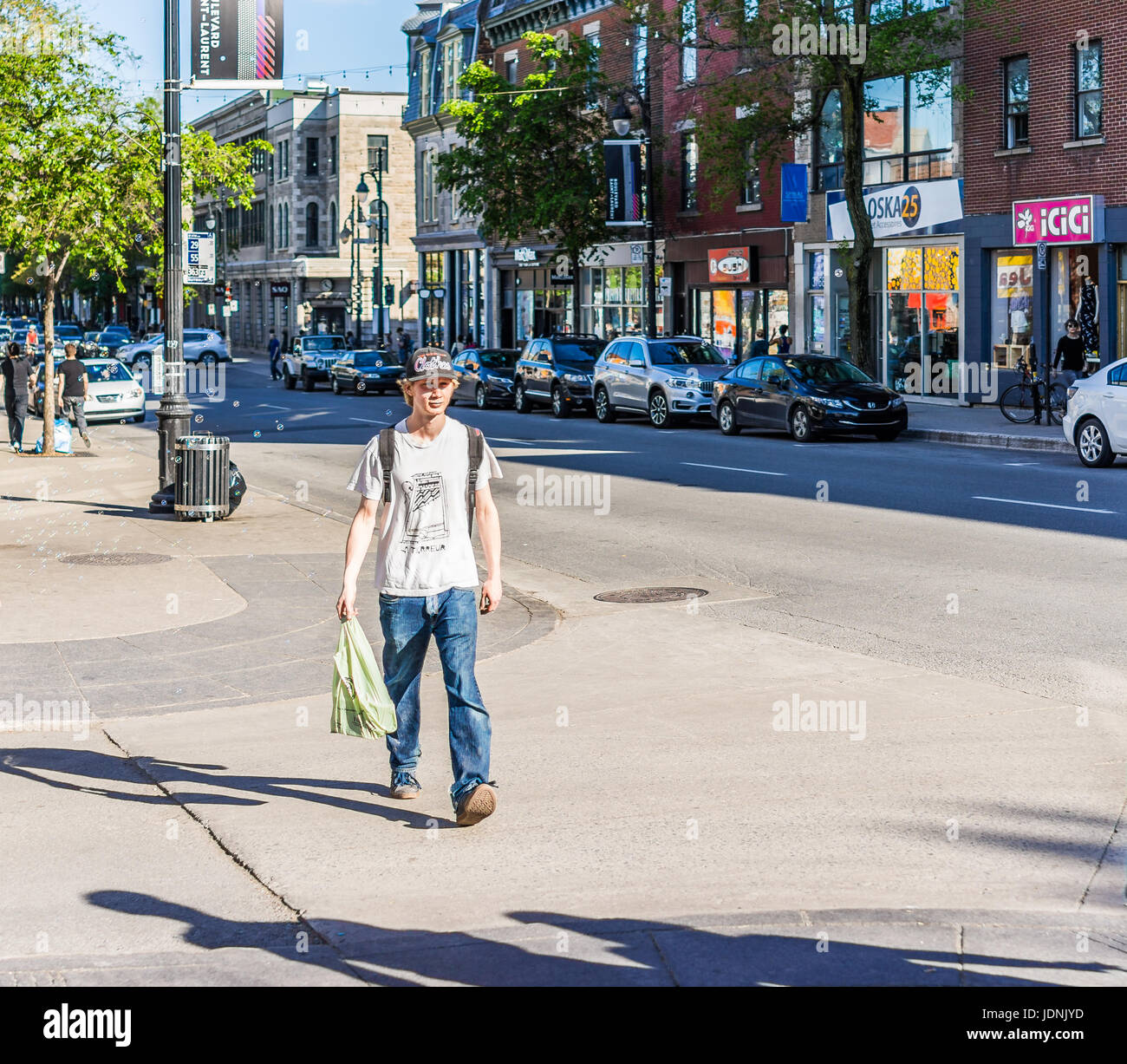 Montreal, Canada - May 27, 2017: Young man crossing street on Saint Laurent boulevard in Montreal's Plateau Mont Royal in Quebec region Stock Photo