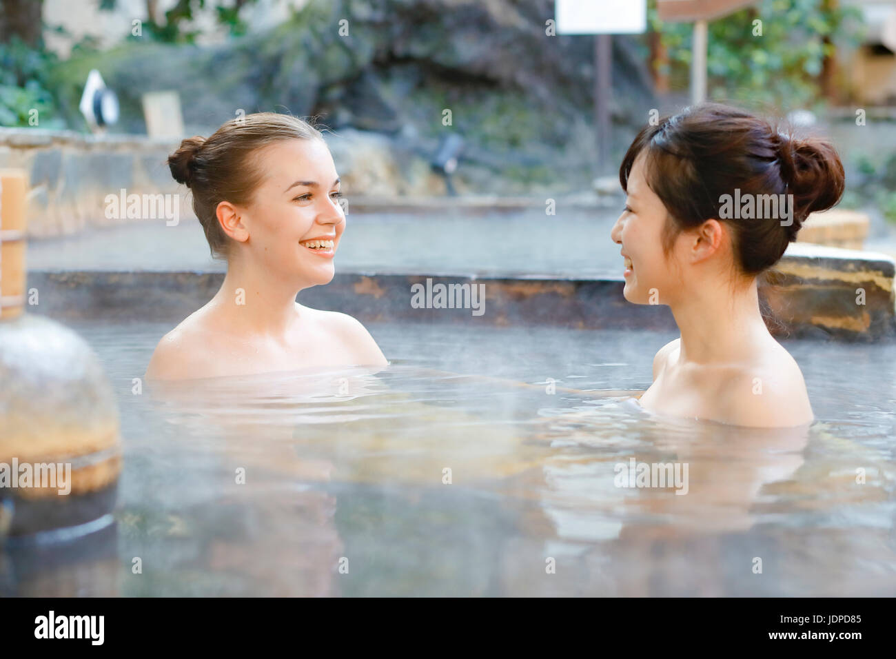Caucasian woman with Japanese friend bathing at traditional hot spring, Tokyo, Japan Stock Photo