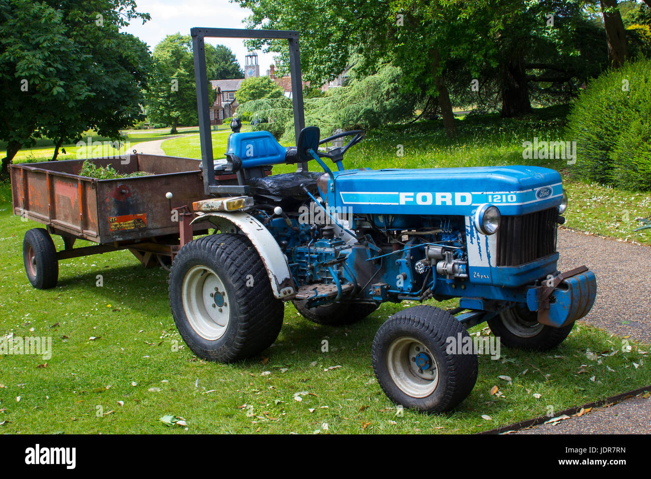 An old but well maintained Ford tractor and box trailer in use daily in the West Dean Estate gardens in West Sussex, England Stock Photo
