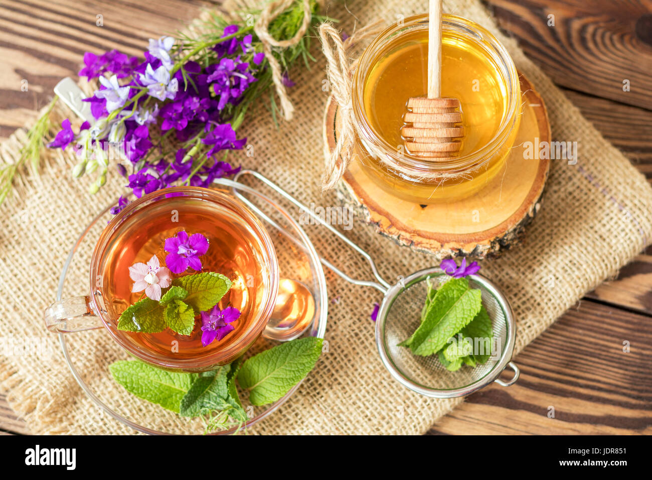 Glass cup of summer herbal tea with fresh mint and field larkspur. Jar