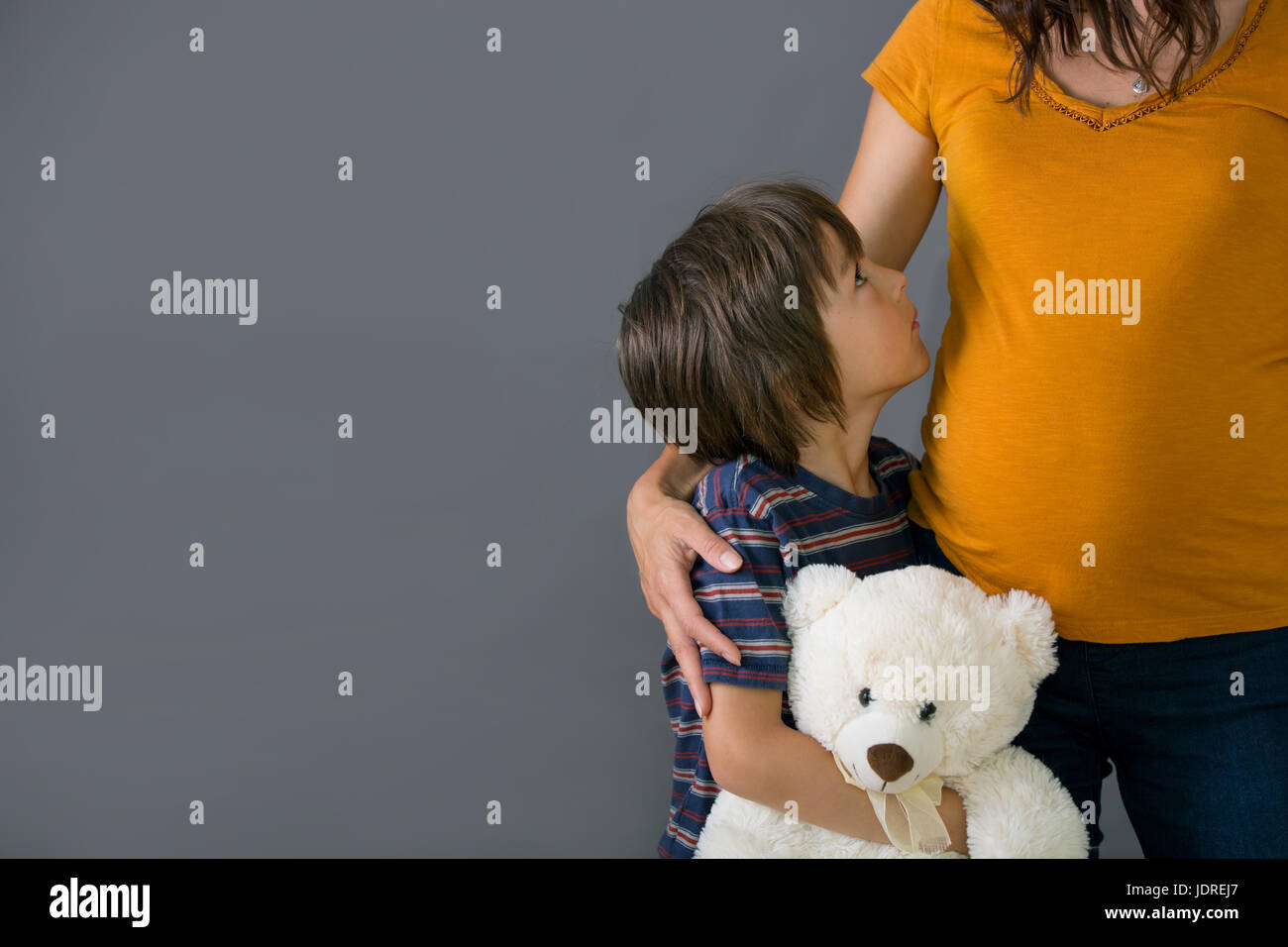 Little child, boy, hugging his pregnant mother at home, isolated image, copy space. Family concept Stock Photo