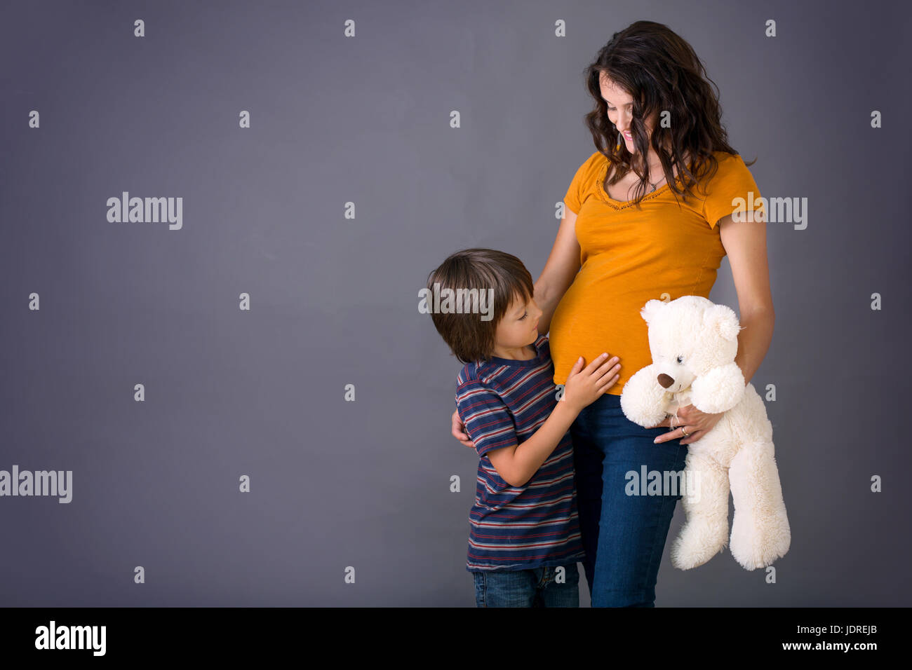 Little child, boy, hugging his pregnant mother at home, isolated image, copy space. Family concept Stock Photo