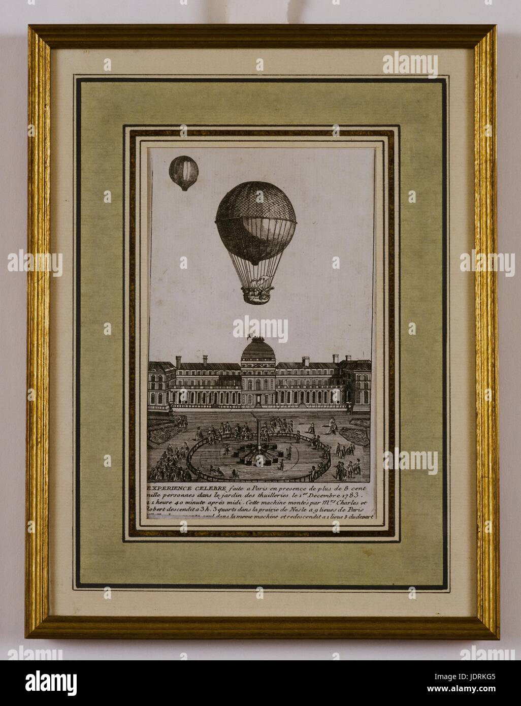 Charles and Robert's balloon experiment in the Jardin des 'Thuilleries' on 1st December 1783. It was preceeded by a pilot balloon sent to test the direction of the wind.  Framed etching (44  x 31.5 cm)  Muller-Quênot Collection  At half-past one, a shot was fired to announce the beginning of the experiment. However nothing happened. The balloon did not take off into the sky and disappointment gradually began to spread through the crowd. Charles approached Etienne Montgolfier, who was present at the experiment. Charles wanted to make up for Etienne's previous public humiliation at the Champs de Stock Photo