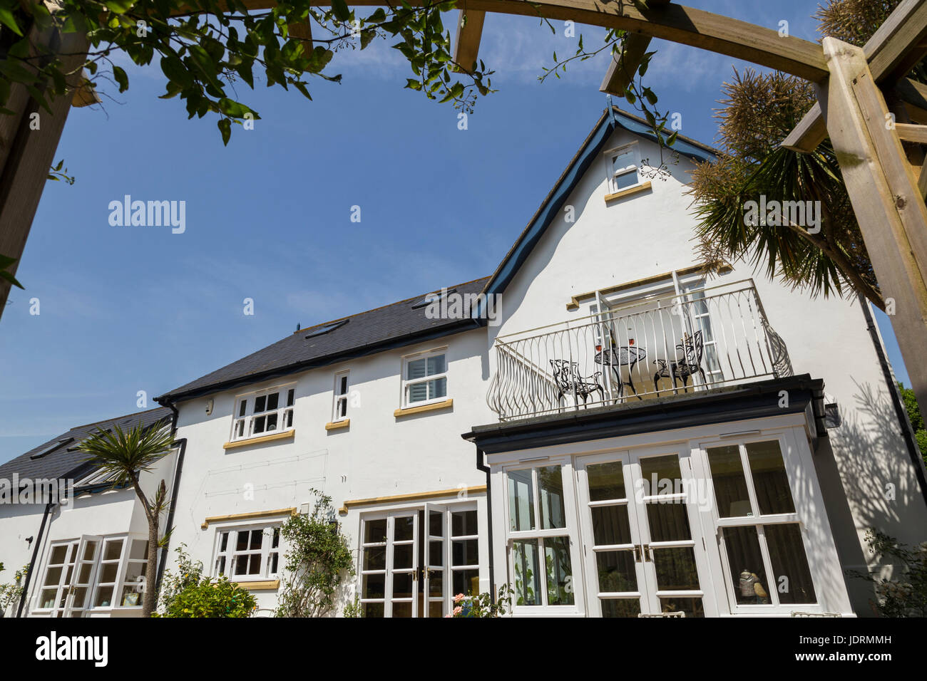 Balcony leading out of the bedroom a white walled house with table,glasses,wine,blue sky in mid summer. Stock Photo