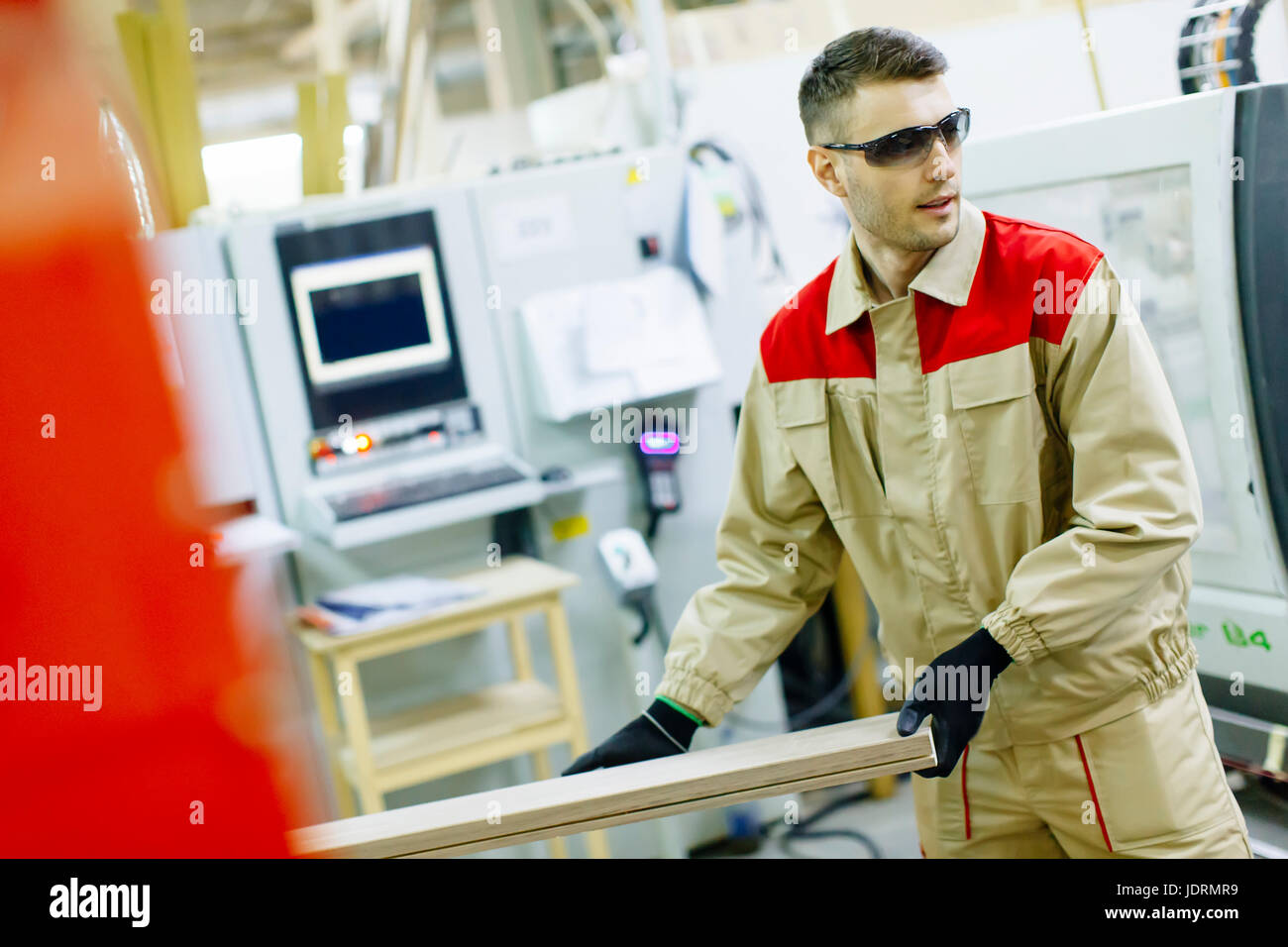 Craftsman wearing working clothes and protective eyewear woodworking in
