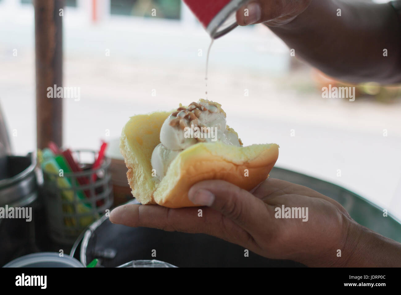 Saler scooping coconut Icecream topped with peanut and milk dressing