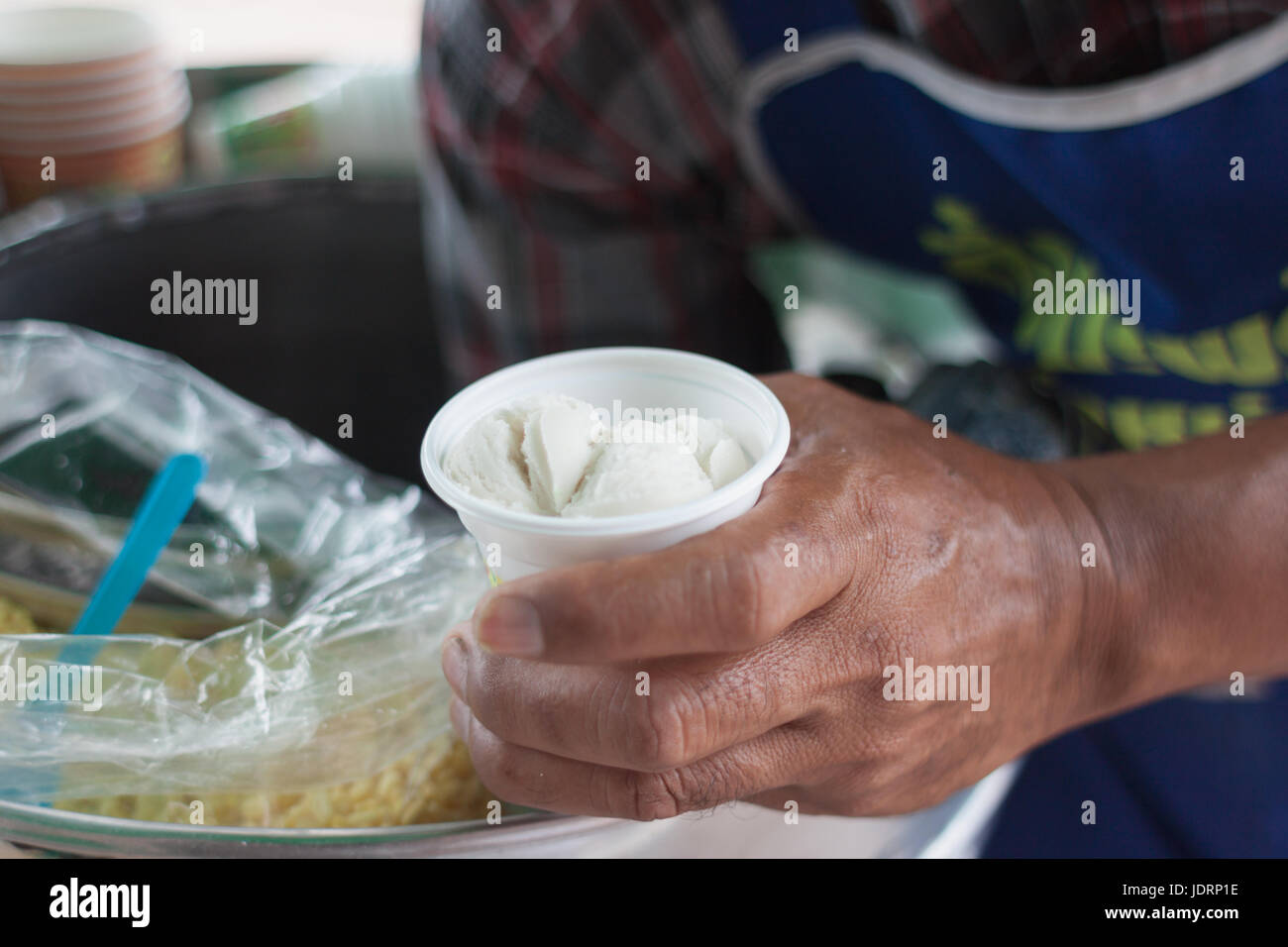 Saler scooping coconut Icecream topped with peanut and milk dressing