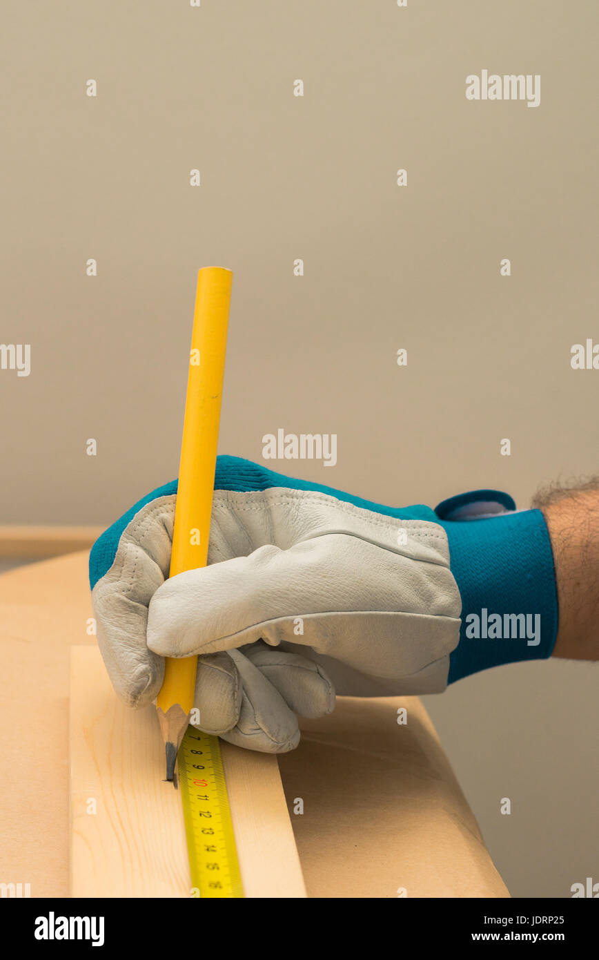 Carpenter handyman using pencil to mark the plank on the woodwork workshop table Stock Photo