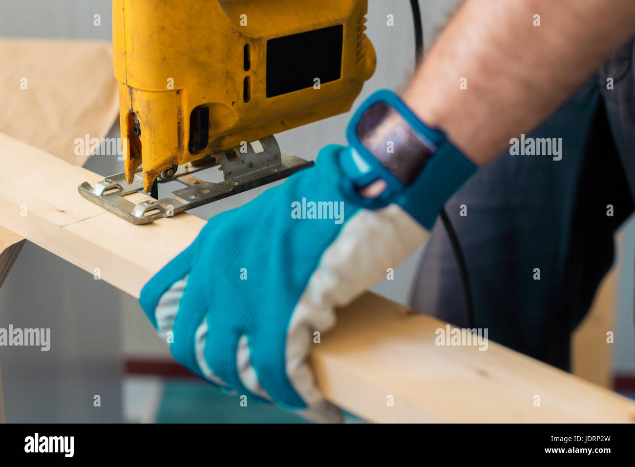 Carpenter handyman using electric handy saw on the woodwork workshop table Stock Photo