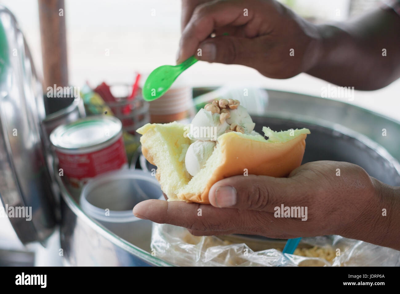 Saler scooping coconut Icecream topped with peanut and milk dressing