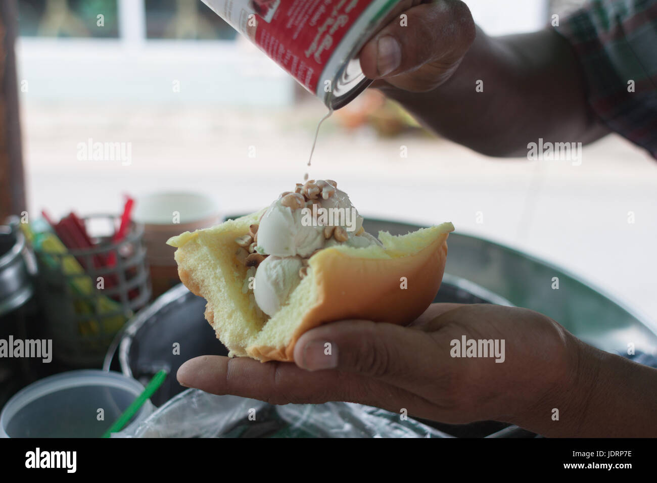 Saler scooping coconut Icecream topped with peanut and milk dressing