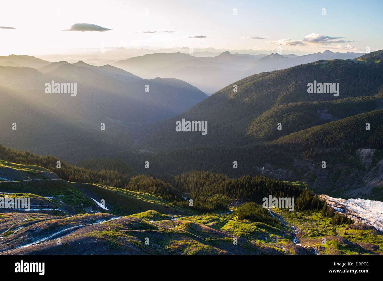 Valley with vibrant sunset light diffusing through a soft mist, silhouetting the hills