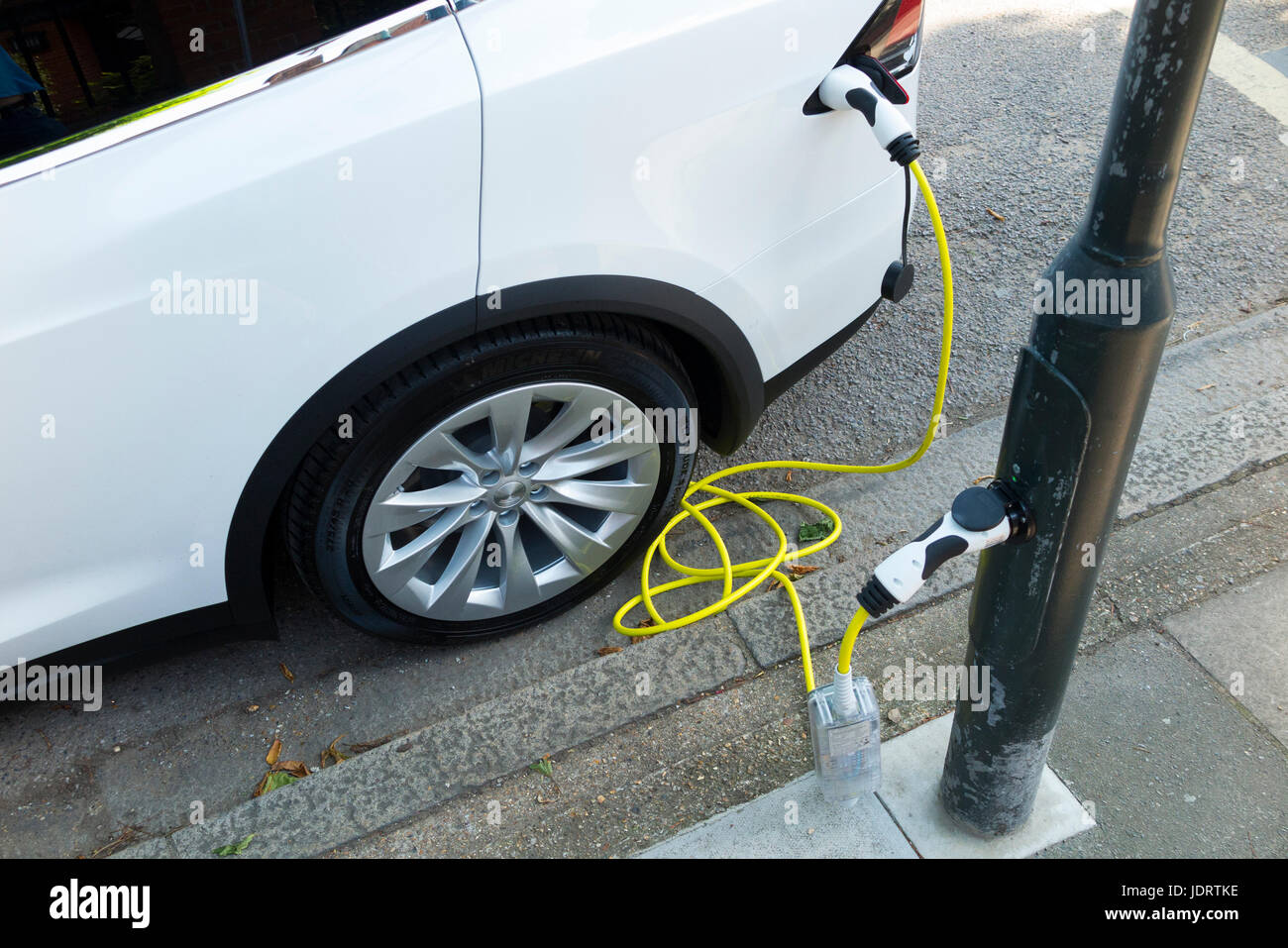 An electric car charger conversion by Ubitricity: smart cable on a street lamp which can now be used to charge an EV vehicle from lamp post (In this case a Tesla.) Twickenham UK Stock Photo