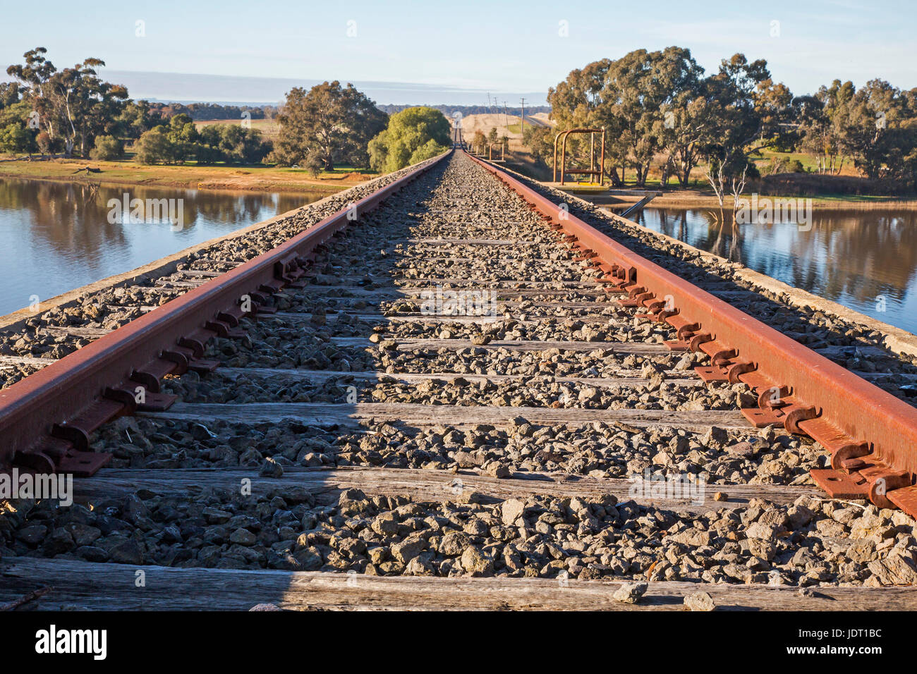 Railway Lines to the Horizon at the Disused Railway Bridge over Joyces Creek at its entry to Lake Cairn Curran. Newstead, Victoria, Australia Stock Photo