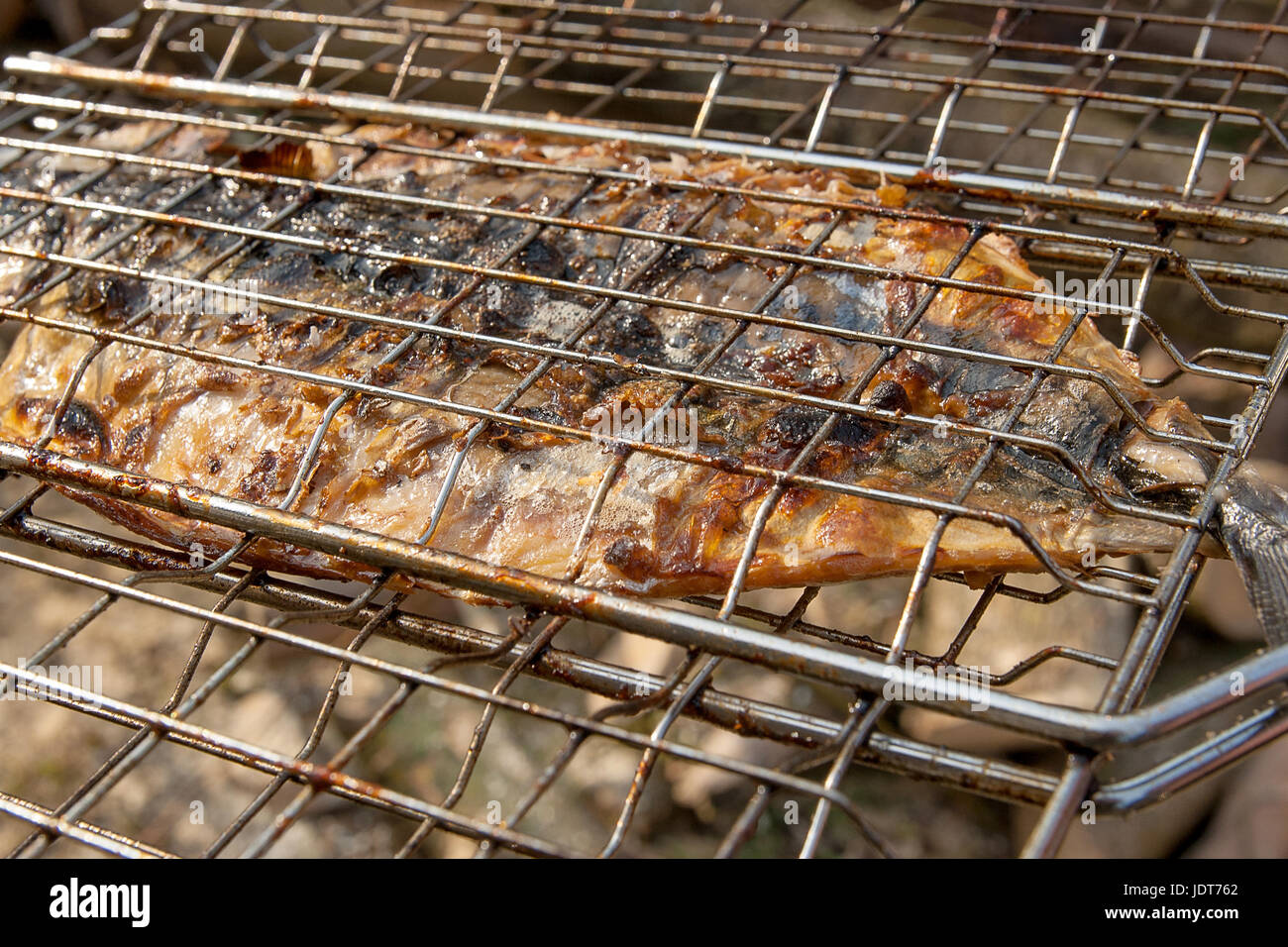 Fresh fish with sauce cooked on an open flame grill. Roasted fish with