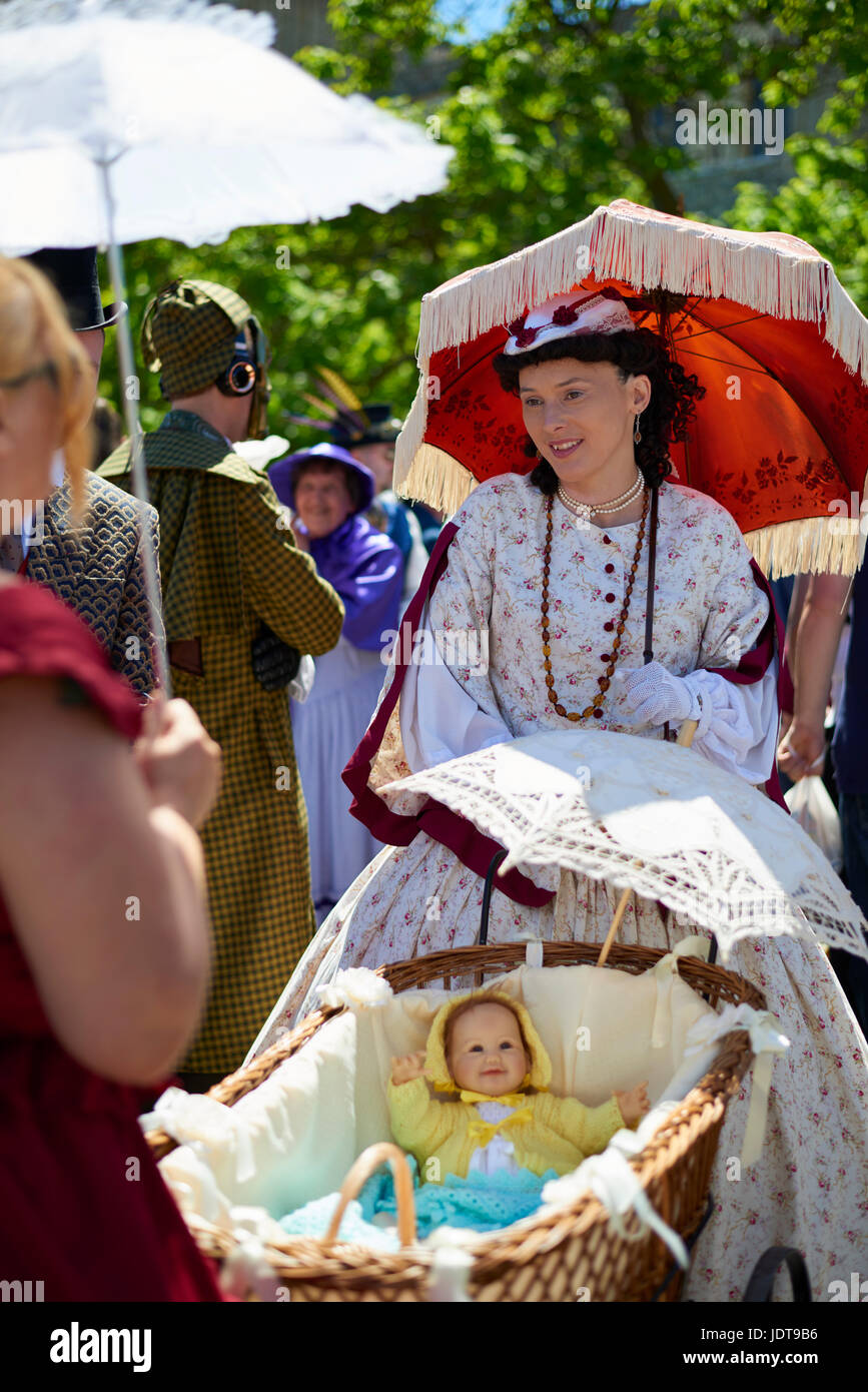 Lady dressed in Victorian costume pushing a pram at Dickens festival Rochester, Kent, England Stock Photo