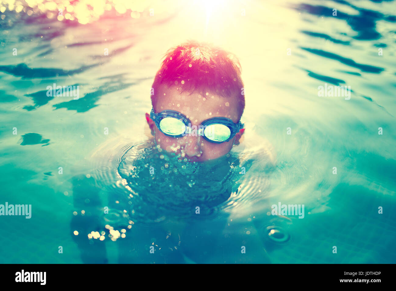 Kid go under water in swimming pool at outdoor sunset, vintage style Stock Photo
