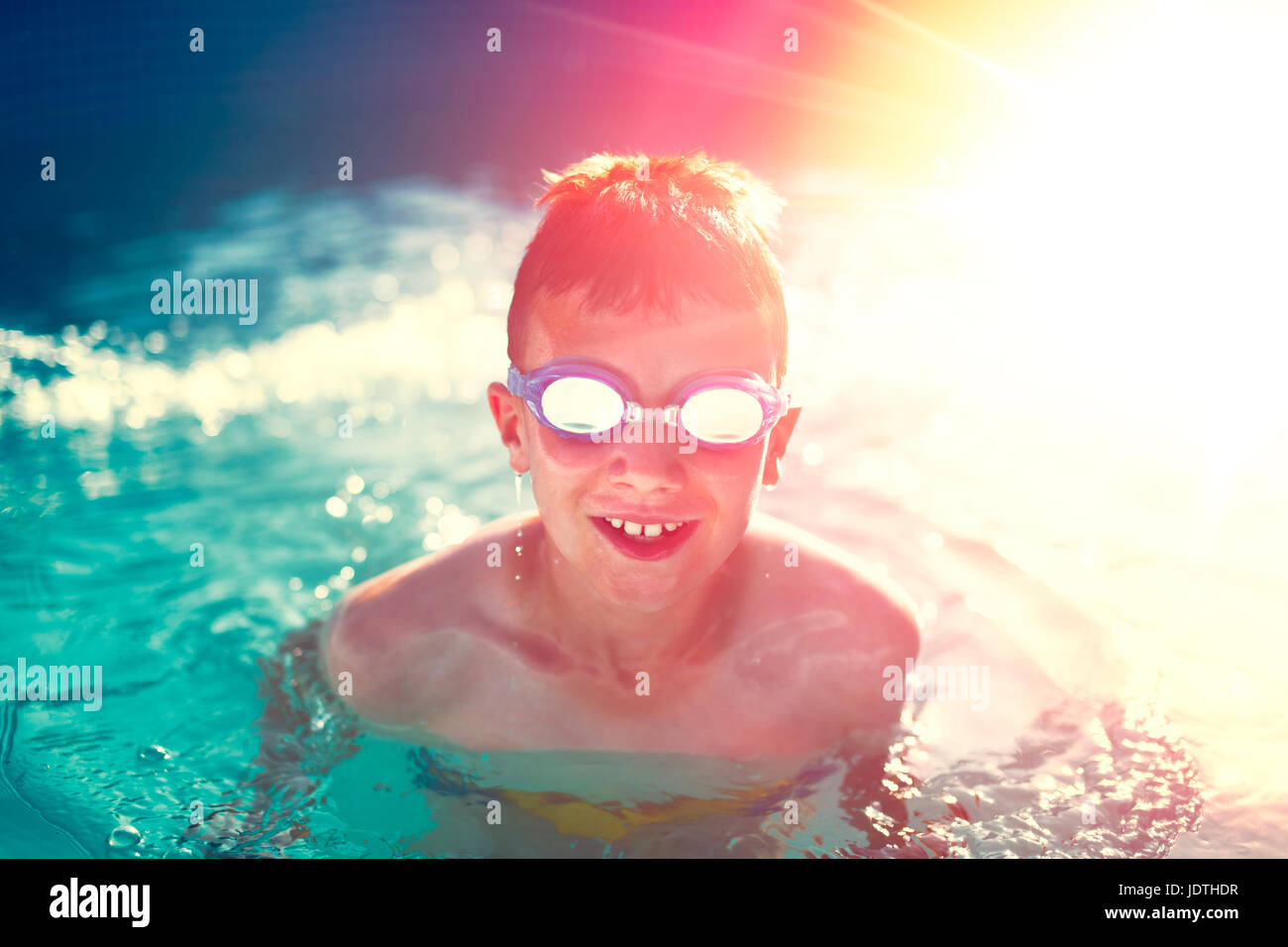 Happy kid in swimming pool enjoying summer holiday in sunset, vintage style Stock Photo