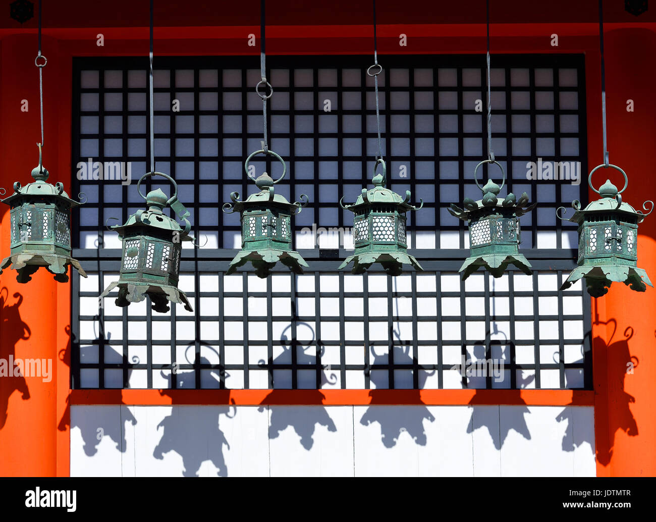 Rows of metal lanterns hanging in Kasuga Taisha Shrine, Nara, Japan, casting their shadows on a wall Stock Photo