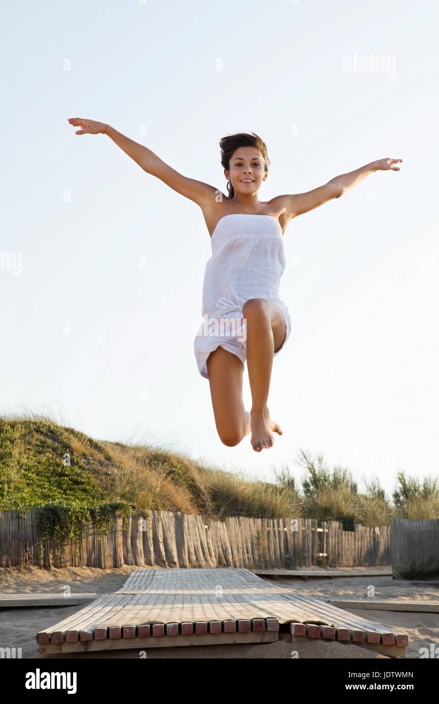 Happy woman jumping over jetty Stock Photo