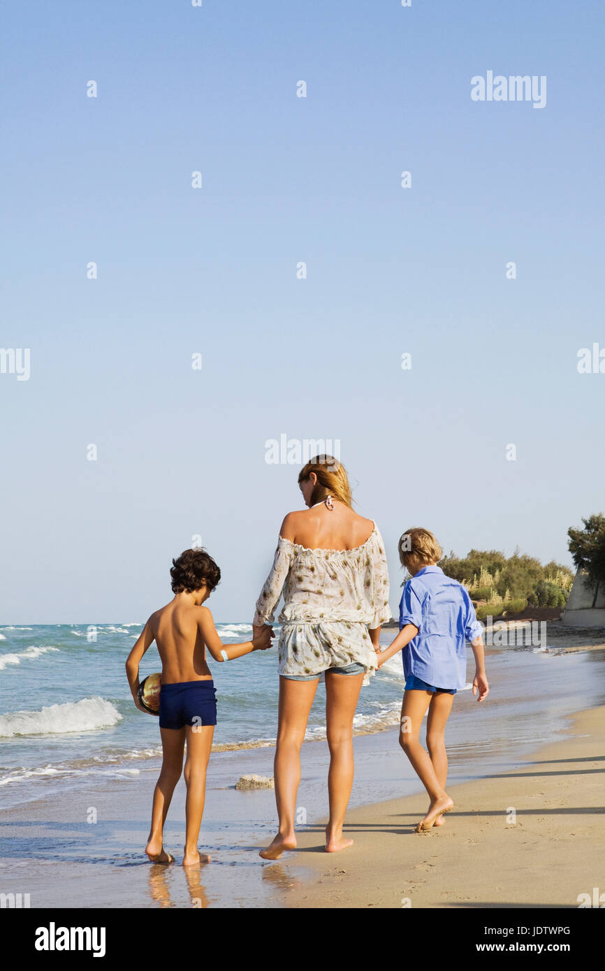 Woman walking with kids on beach Stock Photo