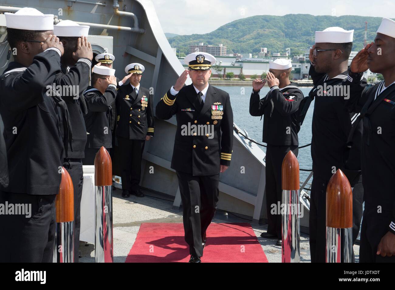 U.S Navy Cmdr. Bryce Benson, center, is welcomed onboard during the change of command ceremony for the Arleigh Burke-class guided missile destroyer USS Fitzgerald May 13, 2017 in Yokosuka, Japan. Stock Photo