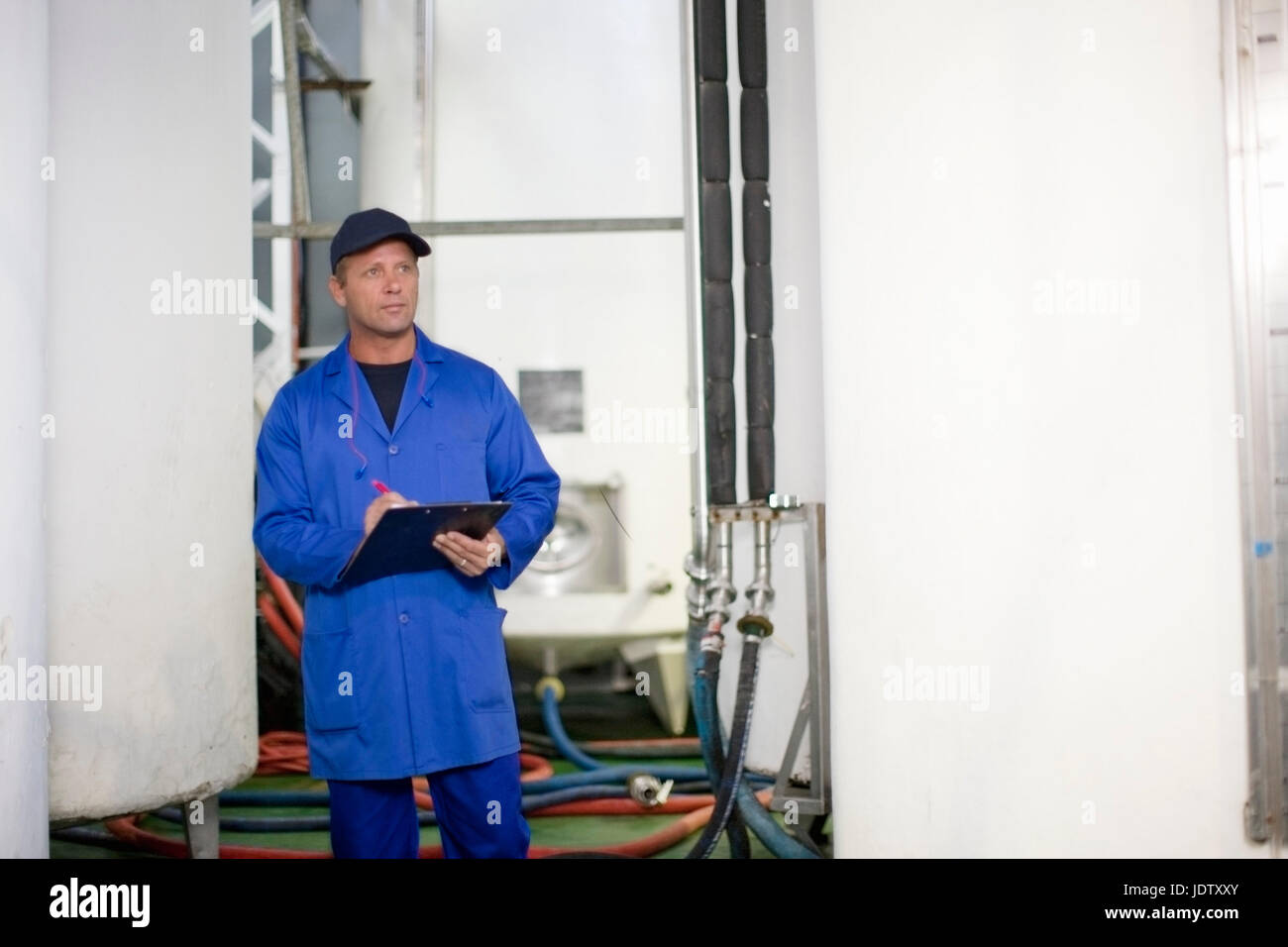 Worker writing on clipboard in factory Stock Photo - Alamy