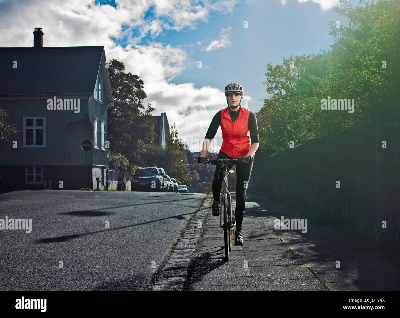 Woman cycling on city street Stock Photo