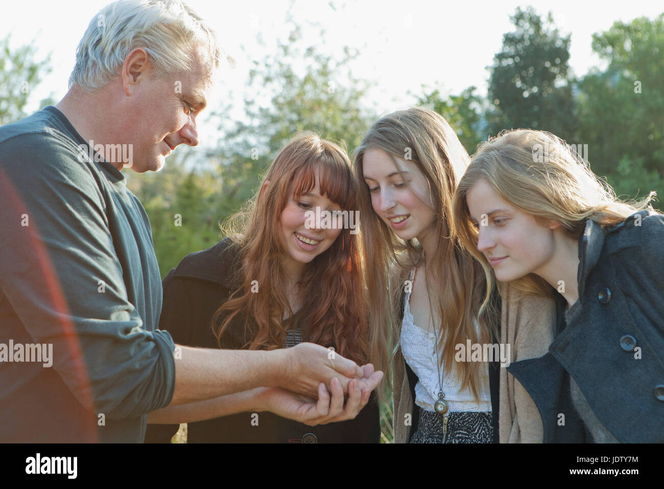 Guy Offering Man offering something to teenage girls Stock Photo - Alamy