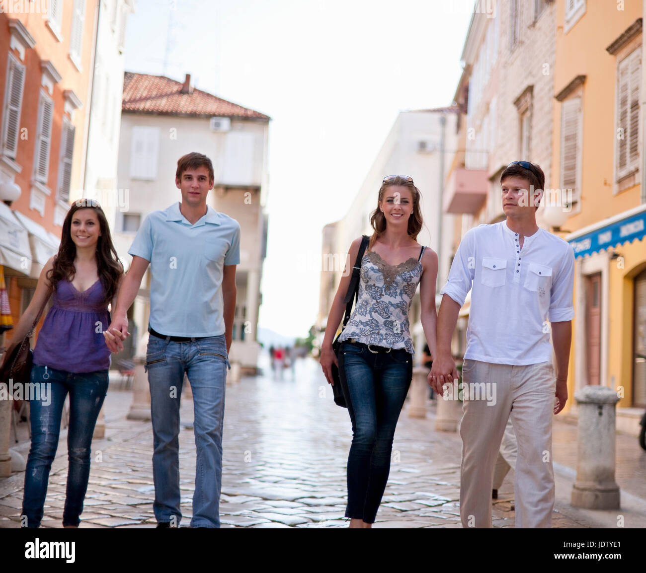 Couples walking on cobbled street Stock Photo