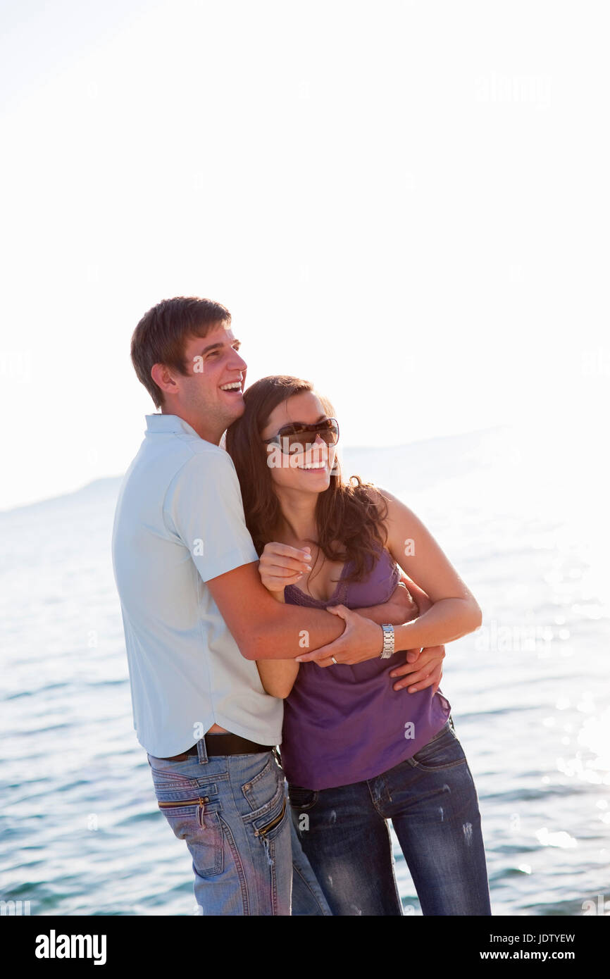 Couple hugging by water Stock Photo