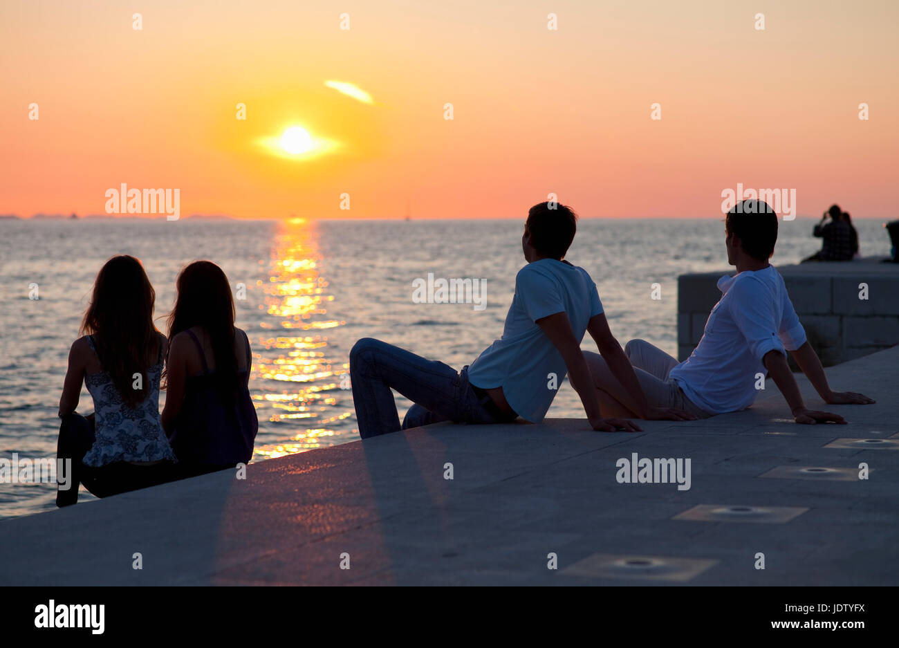 Couples relaxing on pier outdoors Stock Photo