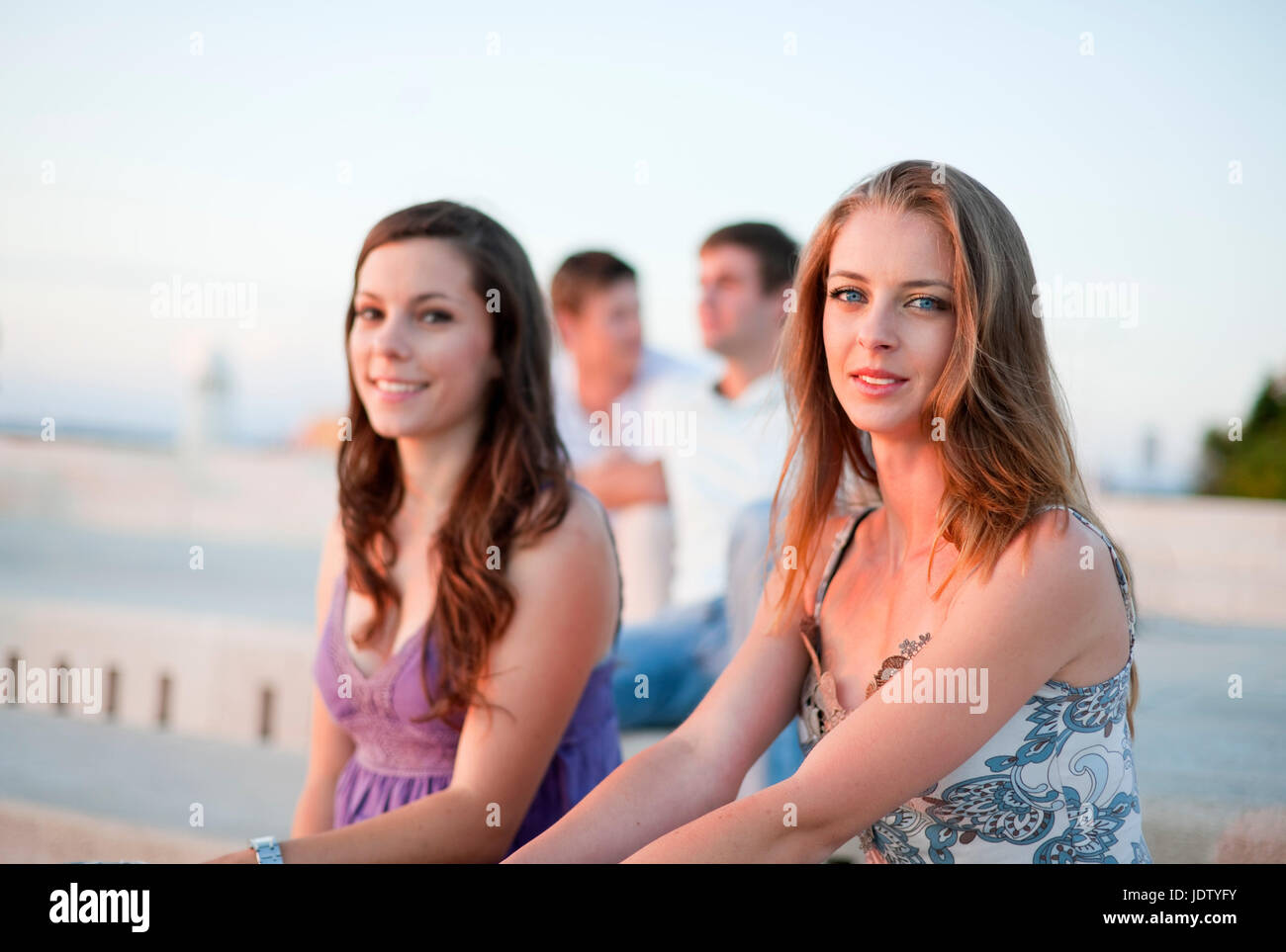 Women sitting on pier outdoors Stock Photo