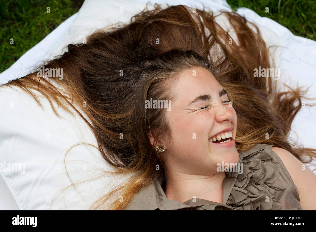Teenage girl laughing on pillows Stock Photo